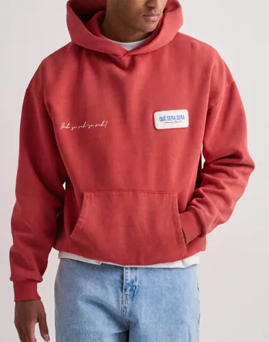 Röd hoodie från Que Sera Sera med tvättad look, magficka och patch på bröstet