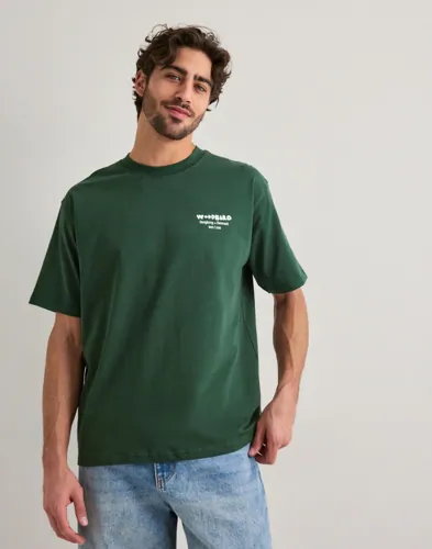 Grön t-shirt från Woodbird med logga på bröstet och tryck i ryggen